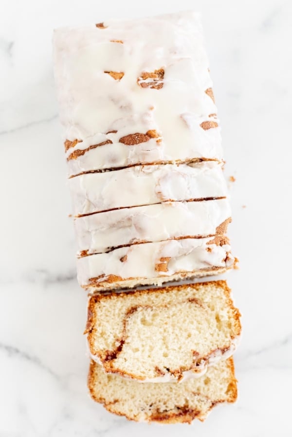 A loaf of 官方正版lm体育APP V7.82.18下载 - 2025最新APP支持安卓IOS，Cinnamon Roll Bread, covered in icing and sliced on a marble surface