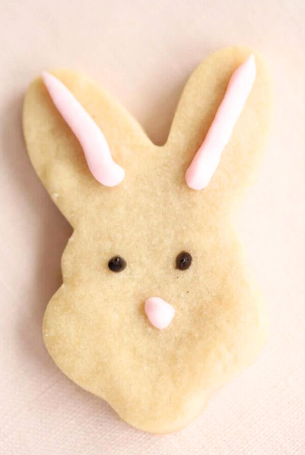 An Easter shortbread cookie in the shape of a bunny face.
